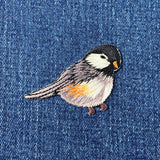 Embroidered bird patch on denim fabric