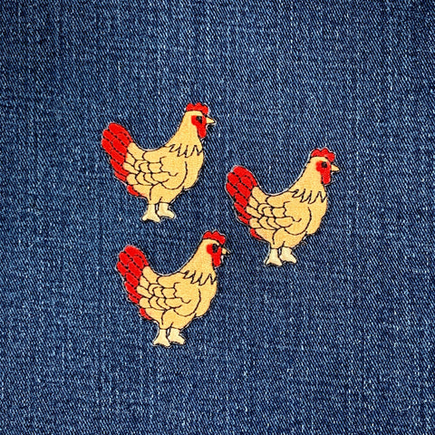 Three embroidered chicken patches on a denim fabric background