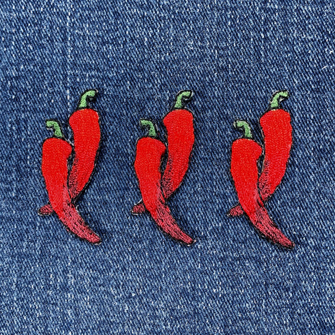 Three red chili pepper patches on denim fabric