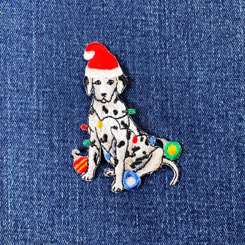 Embroidered patch of a Dalmatian dog wearing a Santa hat on denim fabric.