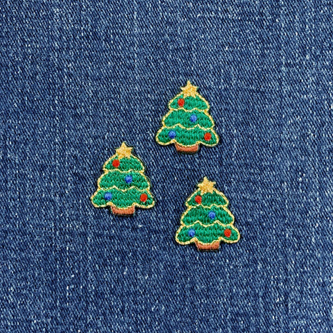 Three embroidered Christmas tree patches on a denim background