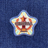 Star-shaped patch with 'CINEMA' text and an award on a denim background