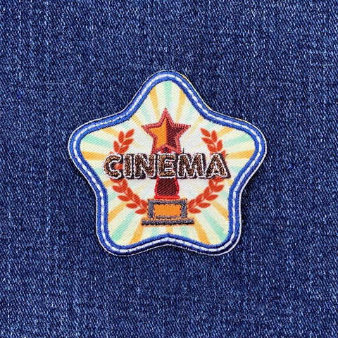 Star-shaped patch with 'CINEMA' text and an award on a denim background