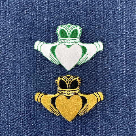 a green and white Claddagh and a black and gold claddagh patch on blue denim fabric
