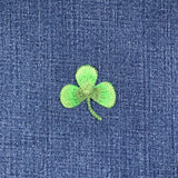 Green four-leaf clover patch embroidered on blue denim fabric
