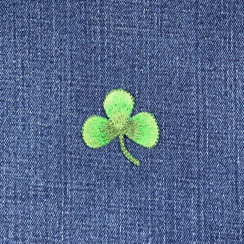 Green four-leaf clover patch embroidered on blue denim fabric