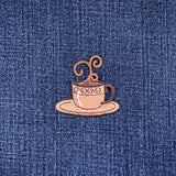 Embroidered patch of a coffee cup and saucer on a denim background