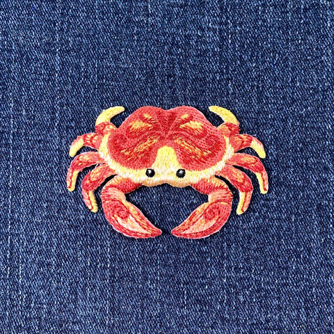 Embroidered crab patch on a denim background