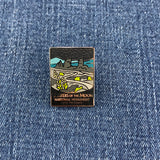 Pin with Craters of the Moon National Monument design on a denim background