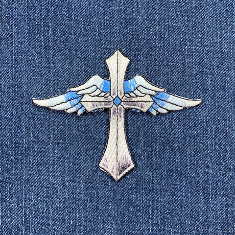 Decorative cross with wings patch on a denim background