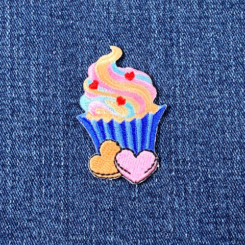 Colorful cupcake patch with hearts on denim fabric