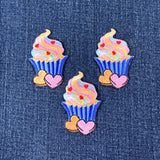 Three colorful cupcake patches with hearts on a denim background