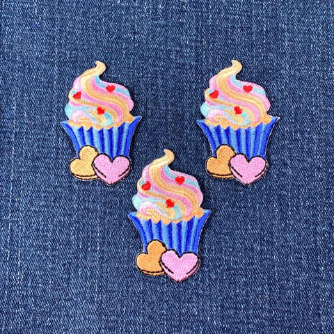 Three colorful cupcake patches with hearts on a denim background