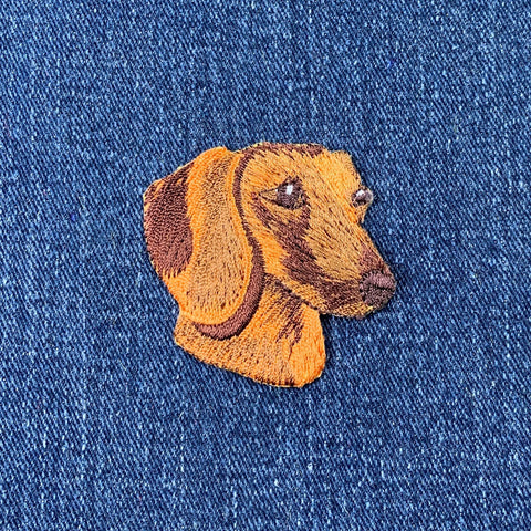 Embroidered patch of a dachshund's head on blue denim fabric