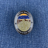 An oval enamel medallion featuring Death Valley National Park, resting on a blue denim fabric background.