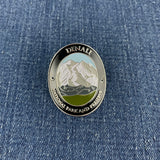 An oval metal enamel medallion featuring a mountain landscape with the text 'DENALI NATIONAL PARK AND PRESERVE' on a blue denim background.