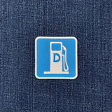 A square embroidered patch featuring a blue gas pump icon with a white border and a blue letter 'D' for diesel in the center, placed on a dark blue denim fabric background.