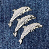 Three dolphin patches on a denim fabric background