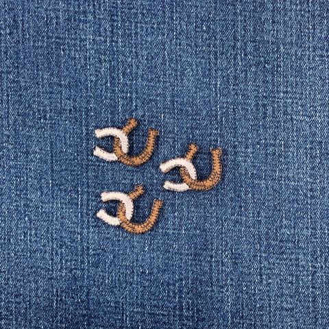 Embroidered horseshoe patches on a denim fabric background
