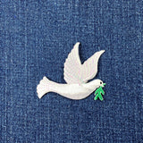 White dove patch with an olive branch on blue denim fabric