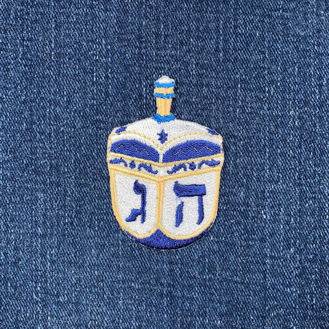 Embroidered dreidel patch on denim fabric