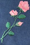 Embroidered pink roses on a denim fabric background