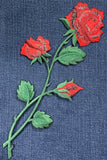 Embroidered red roses with green leaves on denim fabric