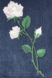 Embroidered white roses on a denim fabric background