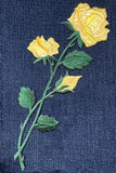 Embroidered yellow roses on a denim fabric background