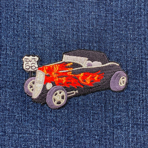 Embroidered patch of a hot rod car with flames on denim fabric