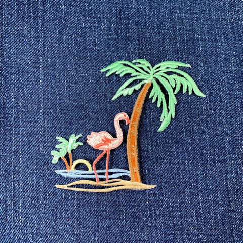 Embroidered flamingo and palm tree patch on denim fabric