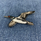 a flying loon embroidered patch on a denim background