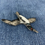a flying loon embroidered patch on a denim background