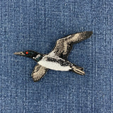 a flying loon embroidered patch on a denim background