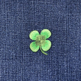 Green four-leaf clover patch on blue denim fabric