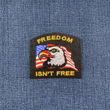 A patch featuring an eagle with a American flag in the background, with the text 'FREEDOM ISN'T FREE' on it, displayed on a denim background