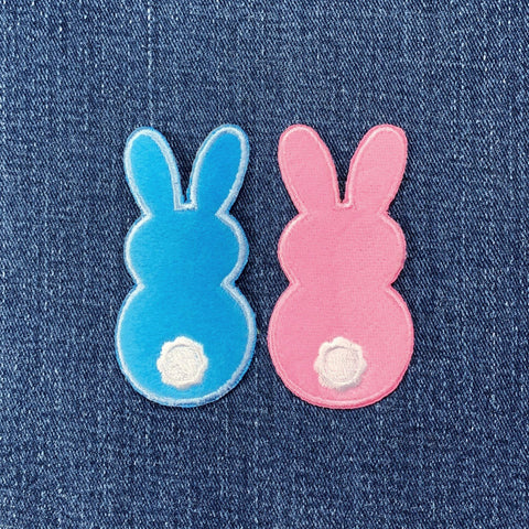 Two bunny-shaped patches, one blue and one pink, on a denim background.