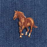 An embroidered iron-on patch featuring a running brown horse with a brown mane and tail, set against a dark blue denim fabric background.
