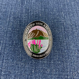 A Walking Stick Medallion featuring a landscape of Gates of the Arctic National Park and Preserve, resting on a blue denim background.