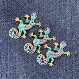 Three colorful gecko patches on a denim background