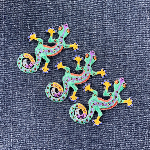 Three colorful gecko patches on a denim background