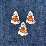 Three embroidered patches depicting a ghost holding a pumpkin with a jack-o'-lantern face on a denim background
