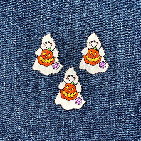 Three embroidered patches depicting a ghost holding a pumpkin with a jack-o'-lantern face on a denim background