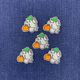 Five identical embroidered patches of a cute cartoon ghost holding an orange pumpkin, decorated with a green hat, arranged on a blue denim fabric background.