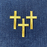 Three gold cross patches on a blue denim background