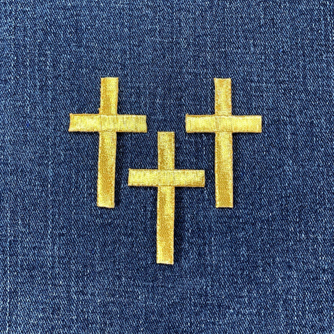 Three gold cross patches on a blue denim background