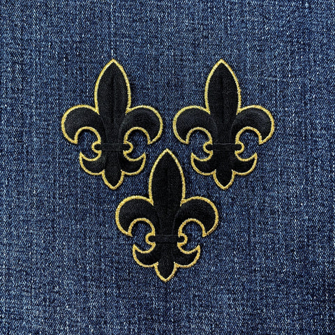Three black and gold fleur-de-lis patches on denim fabric.