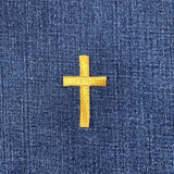 Gold cross patch on blue denim fabric