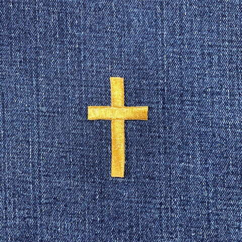 Gold cross patch on blue denim fabric