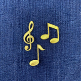 gold note and G clef patches on a denim background